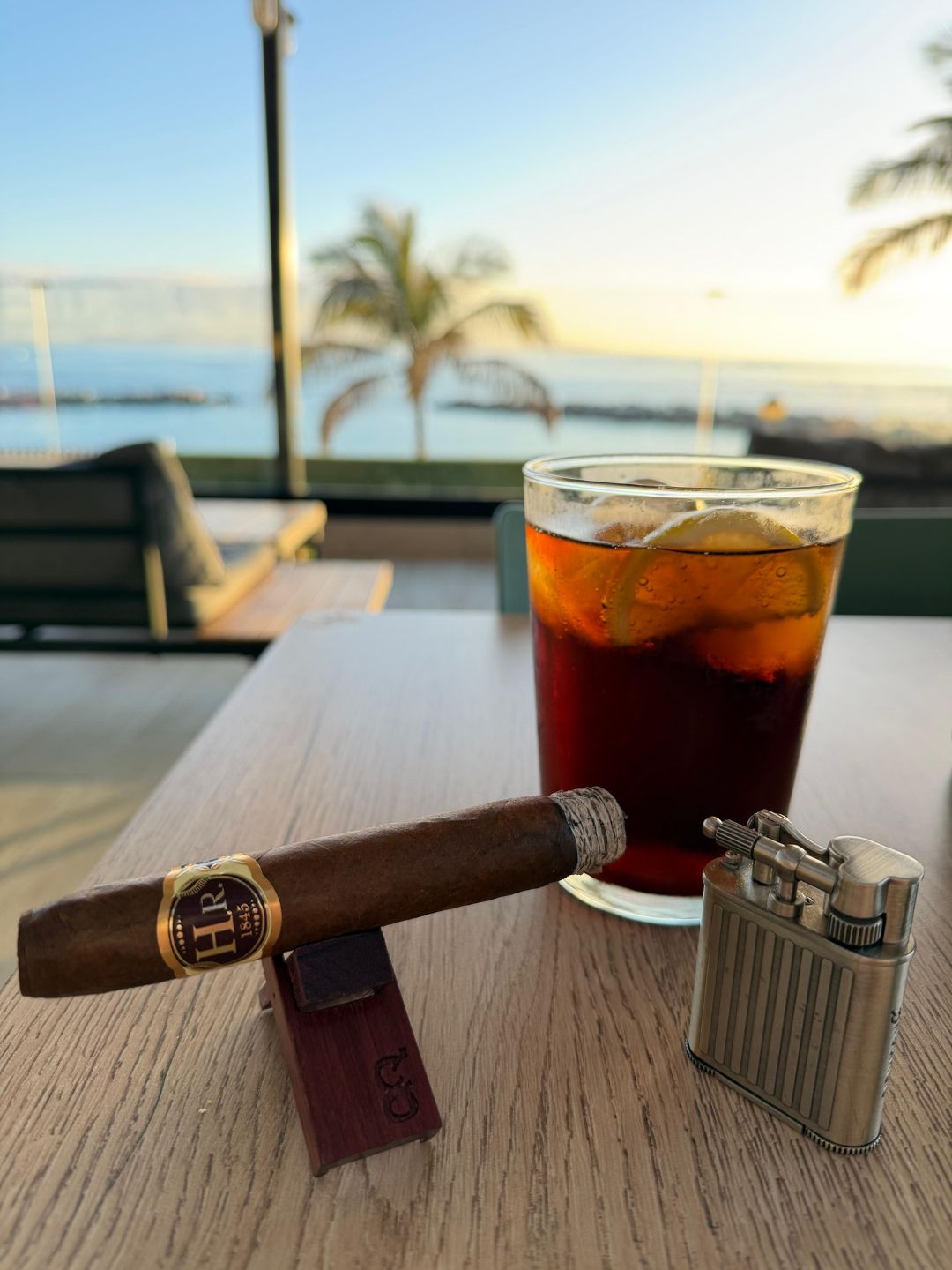 H.R. 1845 Cigar and glass of iced rum & coke on a table with a scenic background