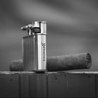 Metal Torch lighter and cigar on a wooden surface with a blurred background