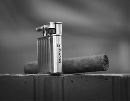 Metal Torch lighter and cigar on a wooden surface with a blurred background