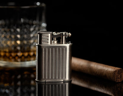 Metal lighter with a cigar and glass on a dark background
